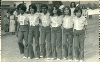 Grupo de estudantes em desfile com a palavra BRASIL sendo formada pelas letras em suas camisas '1960 a 1979