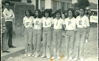 'Estudantes em desfile com a palavra FELIPE escrita pelas letras em suas camisas '1960 a 1979