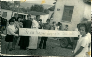 'Estudantes em desfile, sendo um fantasiado de Tiradentes, e uma faixa sendo segurada duas garotas, com os dizeres: Se eu tivesse dez vidas daria todas 1960 a 1979