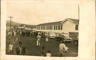 'Multidão em frente o Grupo Escolar Deiró Borges durante sua inauguração, vendo-se 11 automóveis Década 70
