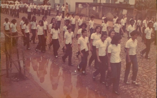 'Desfile cívico de estudantes em uniforme pela Rua Pratinha, vendo-se poça d´água Década  80