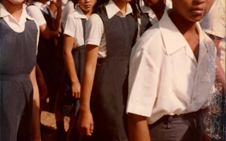 'Estudantes em uniforme durante desfile cívico, vendo-se em primeiro plano Anália, Karina e Neide, uma menina euro-brasileira, uma nipo-brasileira e uma afro-brasileira Década de 80