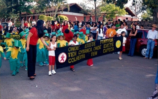 Crianças em desfile cívico carregando faixa e com fantasia de visconde sabugosa durante desfile cívico em frente à escola José Cordeiro de Campos. ano 2000