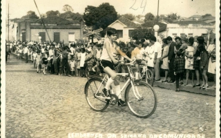 'Marcelo Macedo de bicicleta em desfile cívico pela Rua Dr. Getúlio Portela aos 12 de outubro de 1969, sendo observado por multidão década de 60