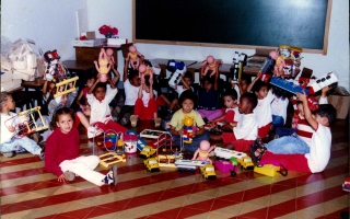 'Entrega de brinquedos para ciranças da rede municiapal de educação, crianças ao chão não identificadas ano 2000
