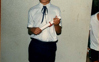 'Formatura dos alunos da Escola Estadual Elizena Leão, aluno não identificado, de pé, uniformizado segurando o diploma  década de 80