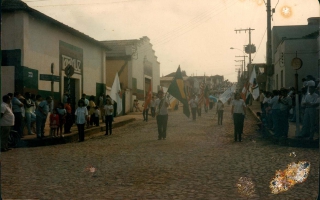 'Alunos segurando várias bandeiras no desfile da cidade década de 80