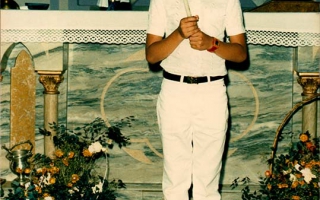 Clécio, vestida com roupas branca  para a primeira eucaristia , segurando nas  mãos uma vela década de 90