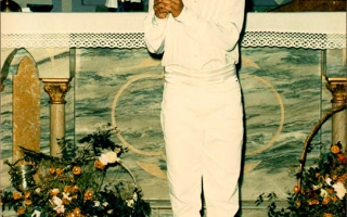 Clécio, vestida com roupas branca  para a primeira eucaristia , segurando nas  mãos uma vela década de 90