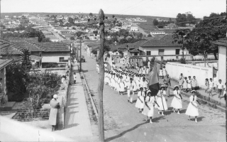 Desfile de estudantes do Educandário Dom Alexandre, vendo-se os bairros Santa Terezinha e Camposaltinhos. 1950-1959
