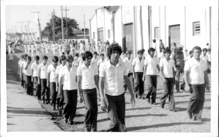 'Estudantes em desfile cívico pela Rua Tiradentes, vendo-se ao fundo os barracões da Cooperativa Agropecuária 1960 a 1979