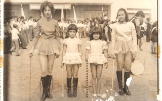 'Adelina, Lídia, Dione, Roseli Campos com trajes de baliza em desfile cívico na Praça Benedito Valadares, vendo-se multidão ao fundo 1960 a 1979