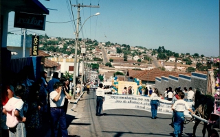 Desfile cívico descendo a Rua Cel. Frederico Franco, vendo-se o casario da cidade e uma grande aglomeração de pessoas em comemoração ao cinquentenário da emancipação política do município. 1994