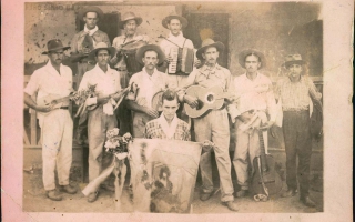 'Pessoas segurando instrumento musicais e bandeira deFolia de Reis década de 80